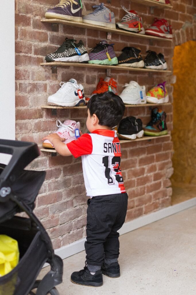 Peuter bekijkt sneakers op wandschappen in de sneakerwinkel aan de Nieuwe Binnenweg in Rotterdam