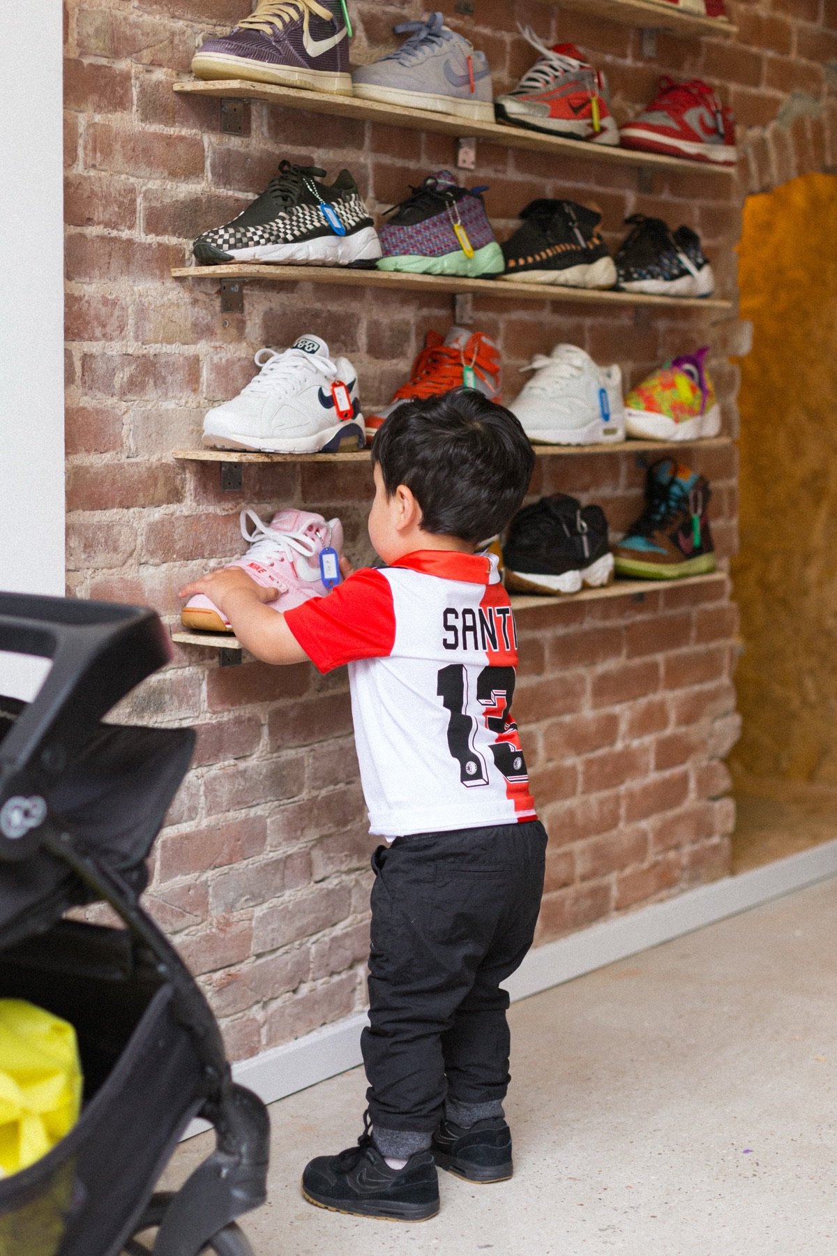 Peuter bekijkt sneakers op wandschappen in de sneakerwinkel aan de Nieuwe Binnenweg in Rotterdam